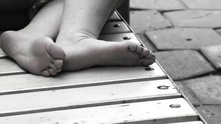 Women's feet on a park bench.