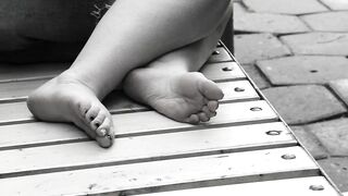 Women's feet on a park bench.