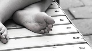 Women's feet on a park bench.