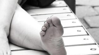 Women's feet on a park bench.